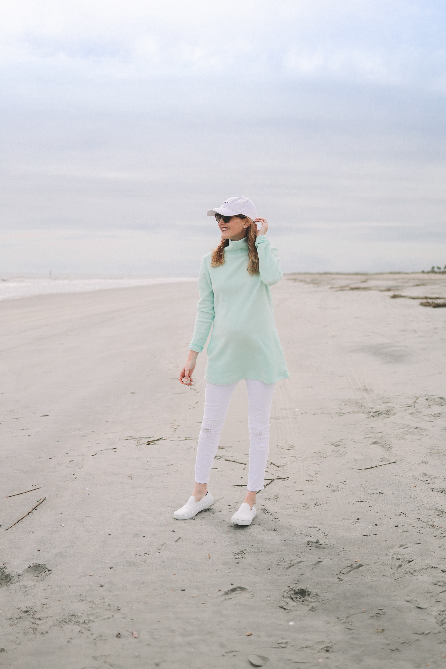 Kelly Larkin’s outfit: Dudley Stephens Cobble Hill Turtleneck / J Brand Maternity Ankle Jeans / Rothy’s Machine-Washable Sneakers / Vineyard Vines Hat