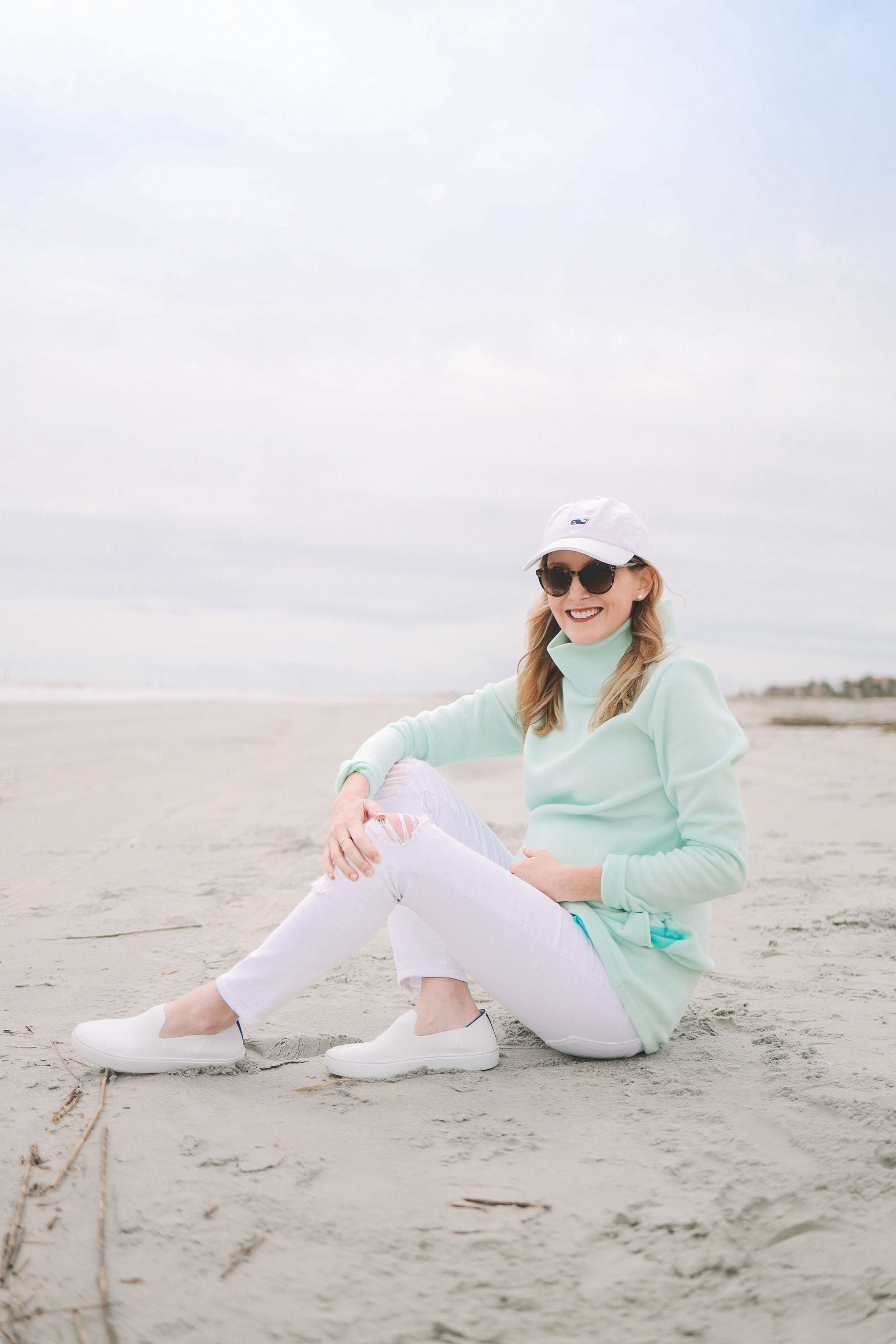 Kelly Larkin’s outfit: Dudley Stephens Cobble Hill Turtleneck / J Brand Maternity Ankle Jeans / Rothy’s Machine-Washable Sneakers / Vineyard Vines Hat