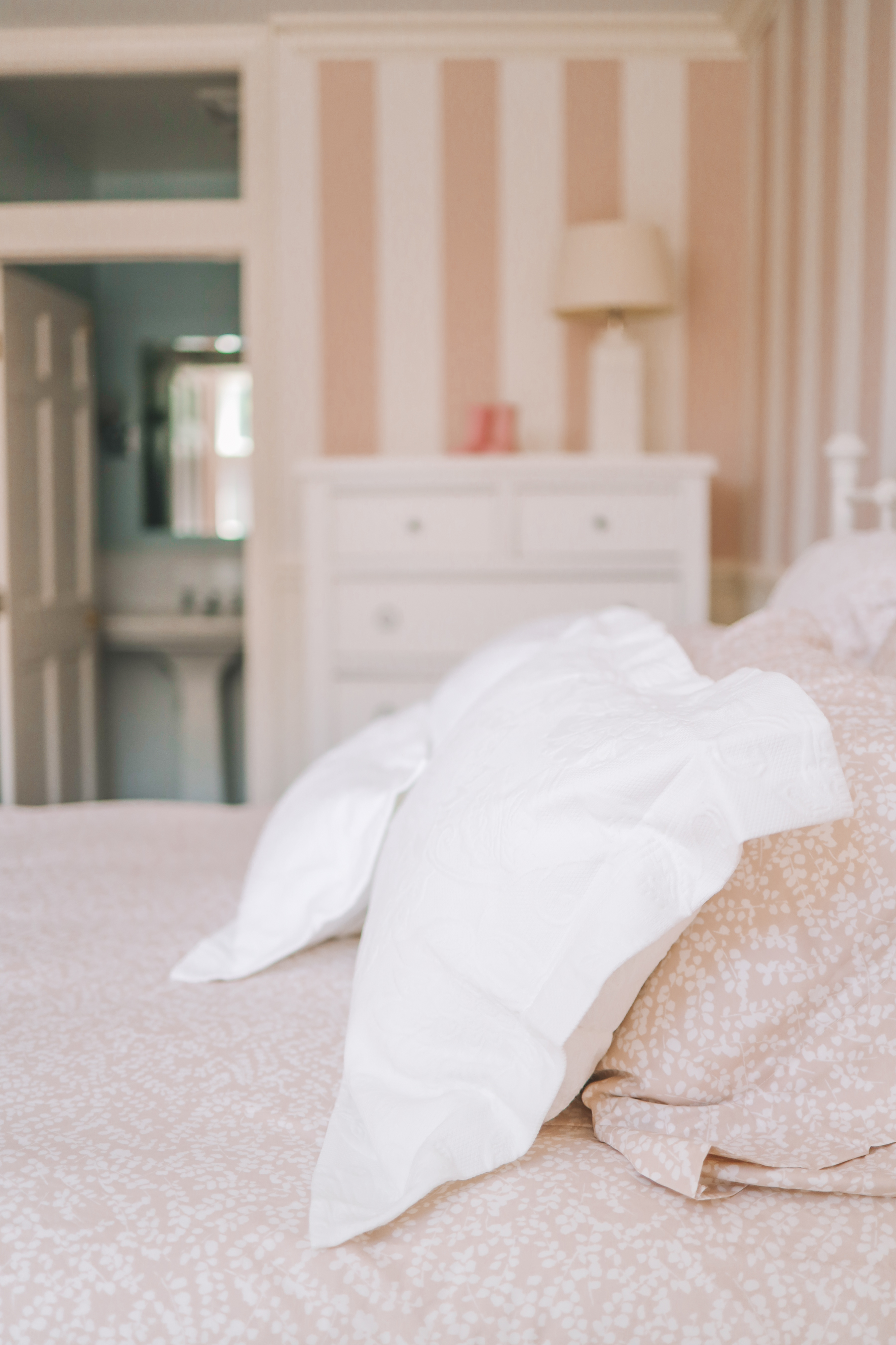 A sideview of bedding, white pillows on pink sheets
