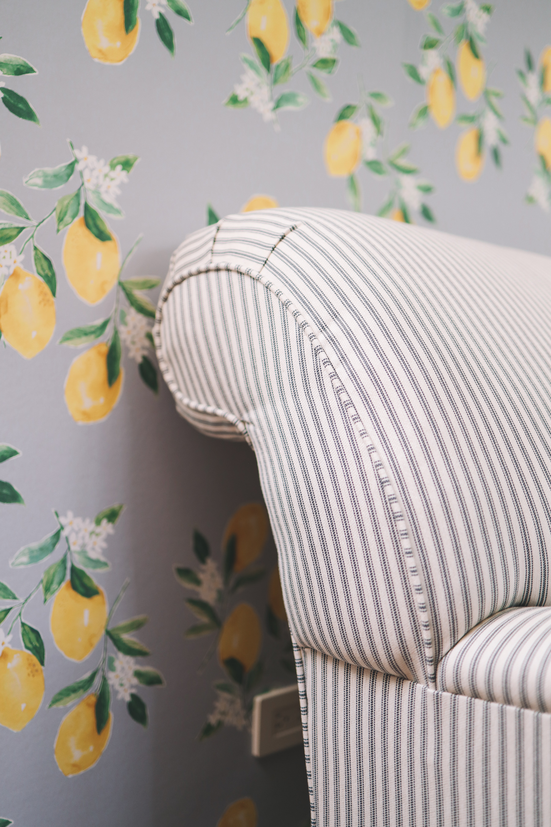 A lemon wallpaper adds a zest to the stripes in the loveseat