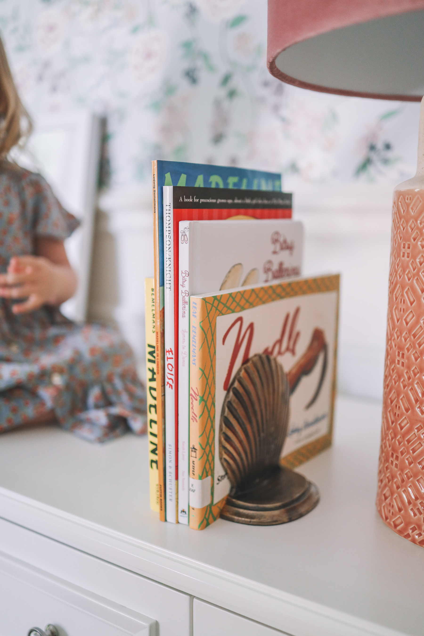 up close of books on a dresser with floral wallpaper