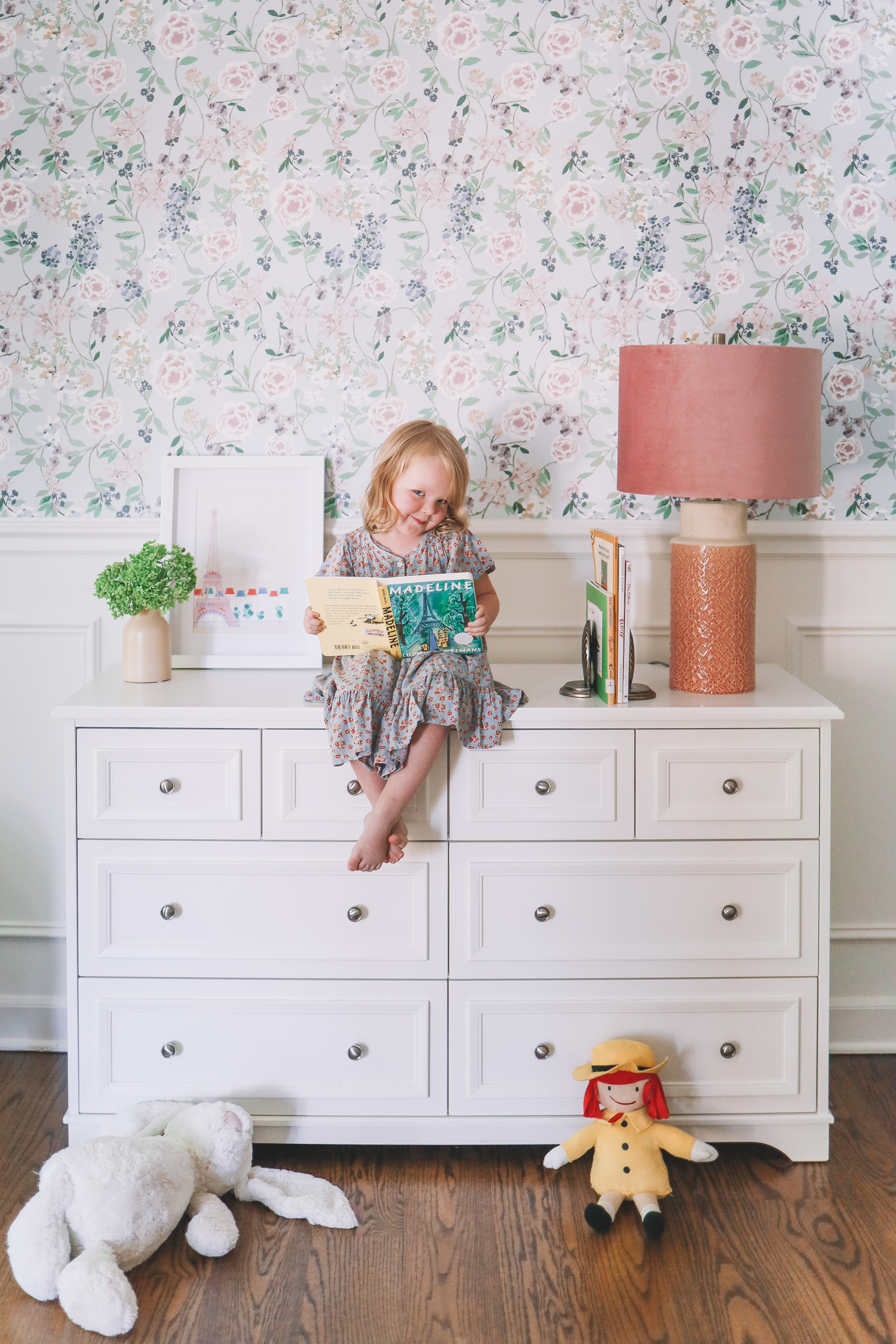 a little girl on a white dresser who is reading