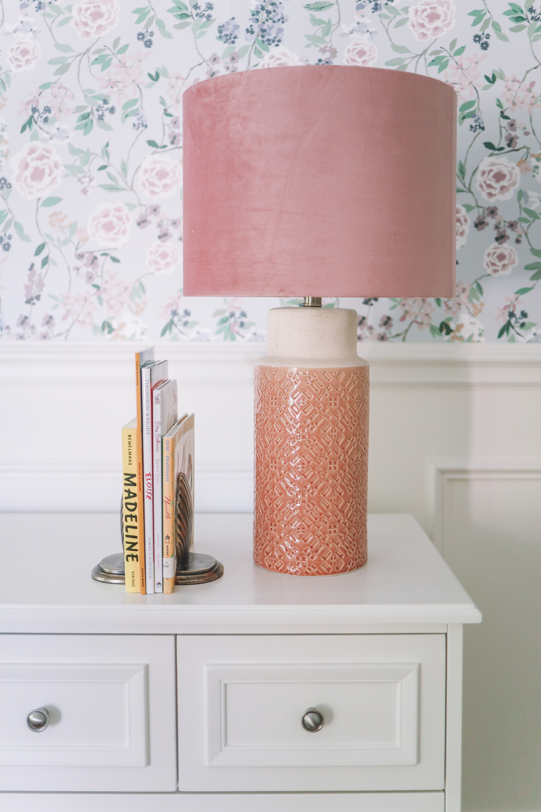 a white dresser with a pink lamp