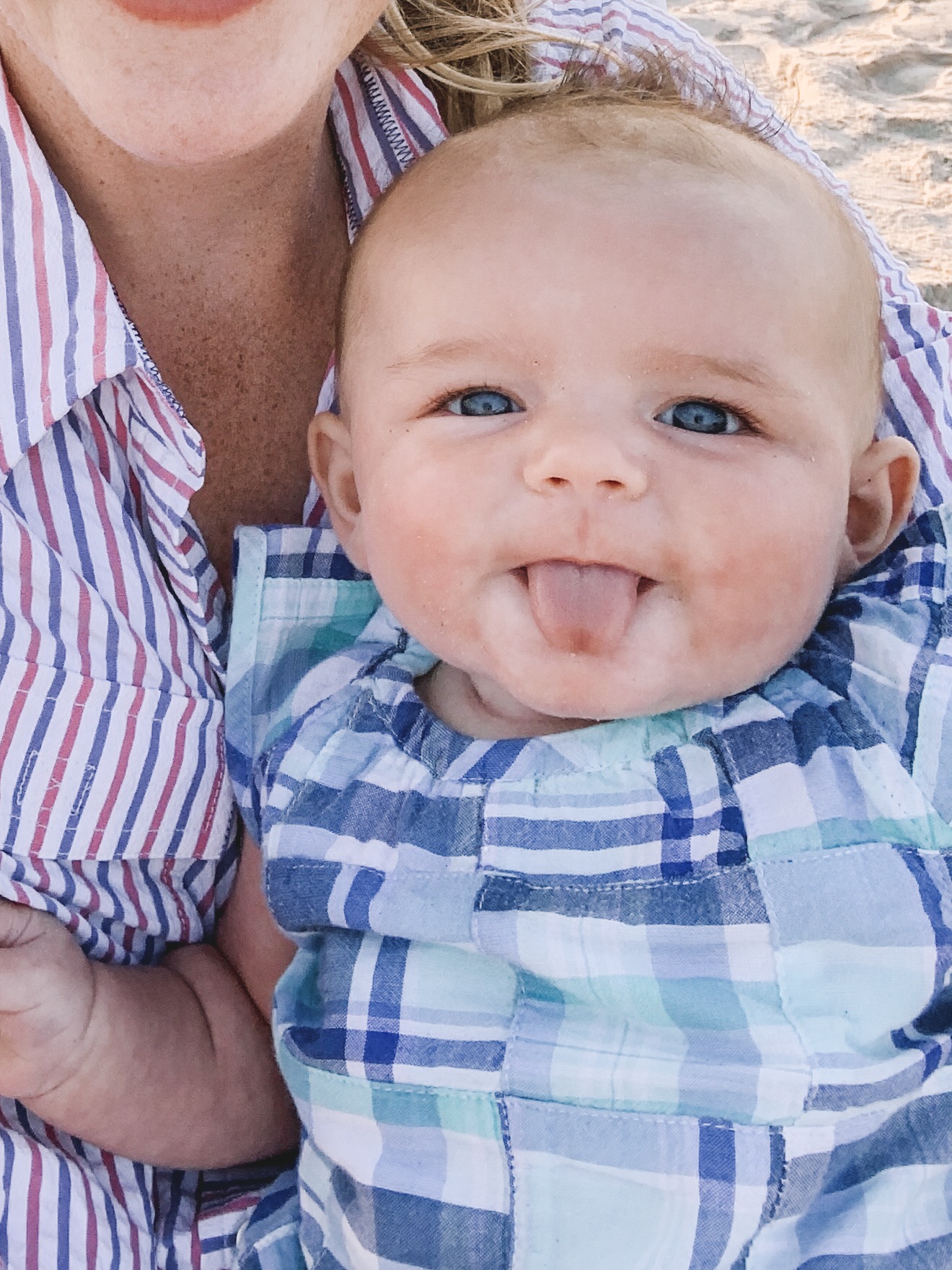 A baby sticks her tongue out while her mom holds her