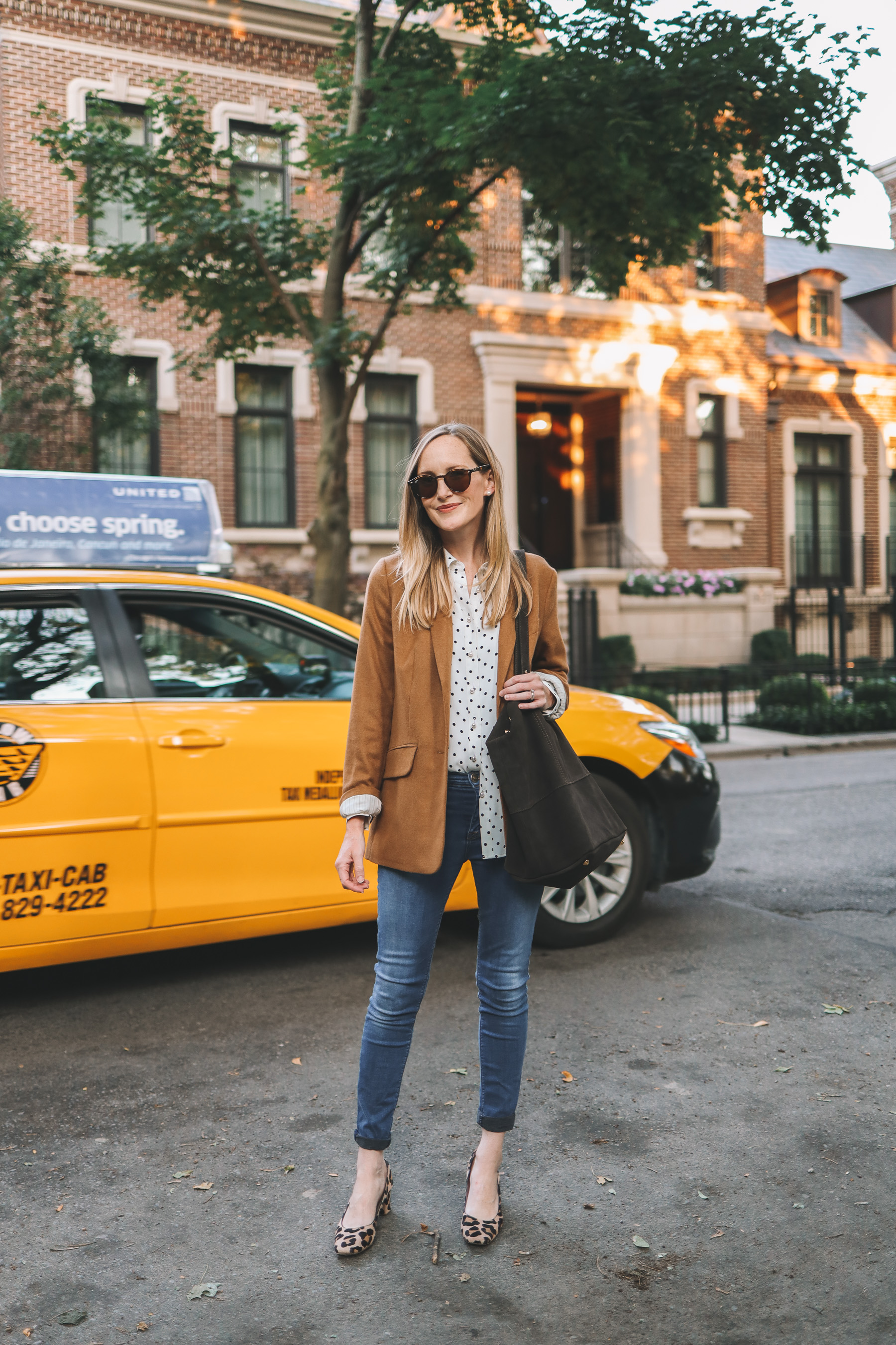 a girl in the street wewaring a Mark & Graham Amalfi Italin Suede Tote and a yellow cab in the back