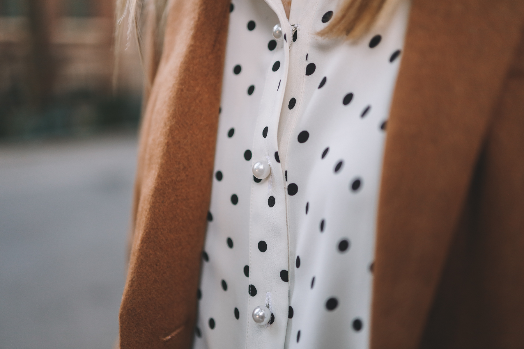 an up close of a polka dot button down with pearls