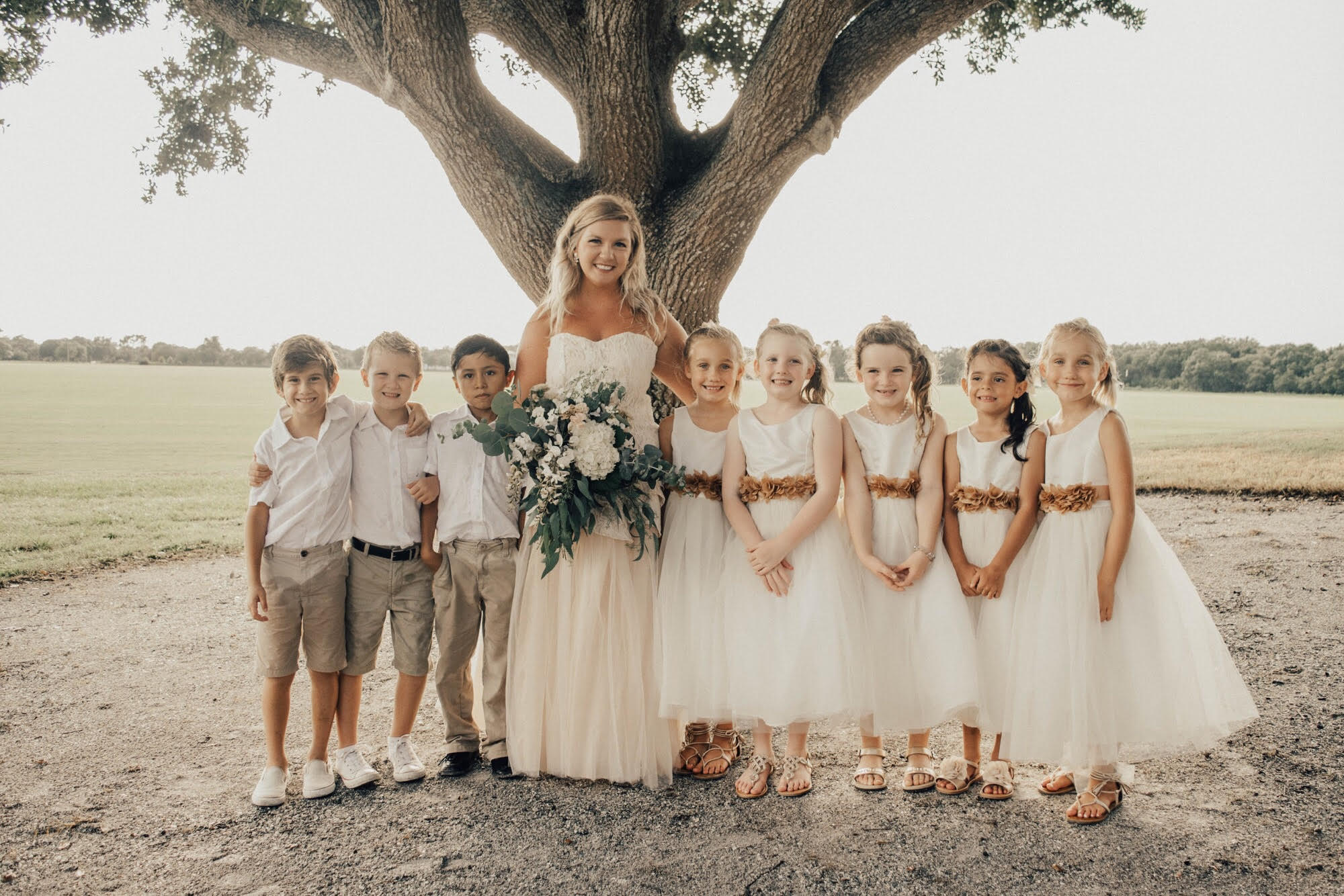 a woman in a white dress with lots of little children around her