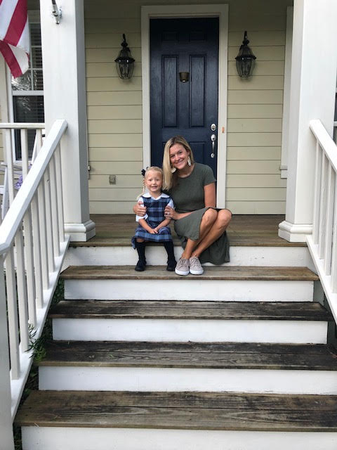 a mom and a little girl in front of their house