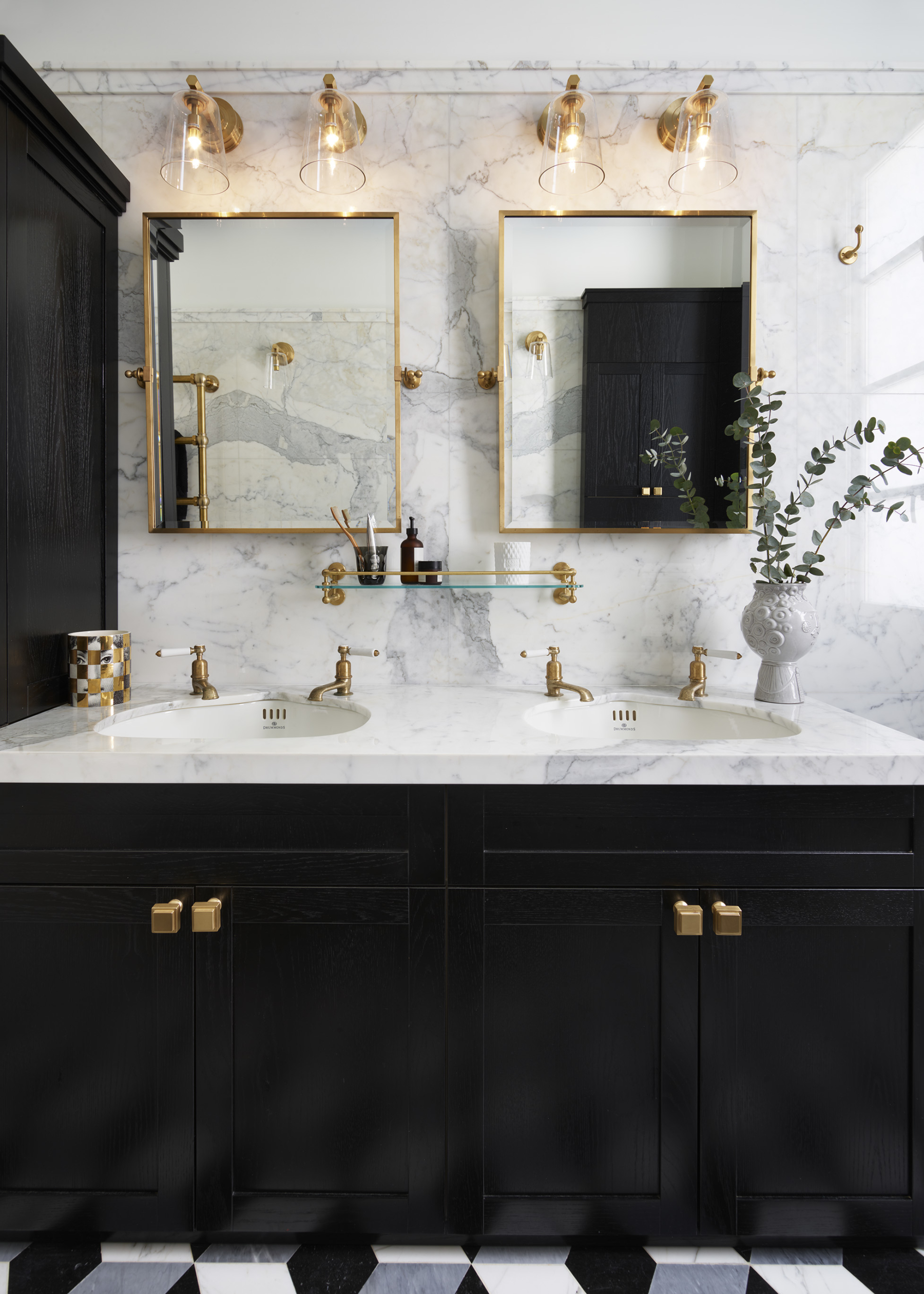 Gold and black contemporary bathroom features a brass waste basket placed  beneath on black and wh…