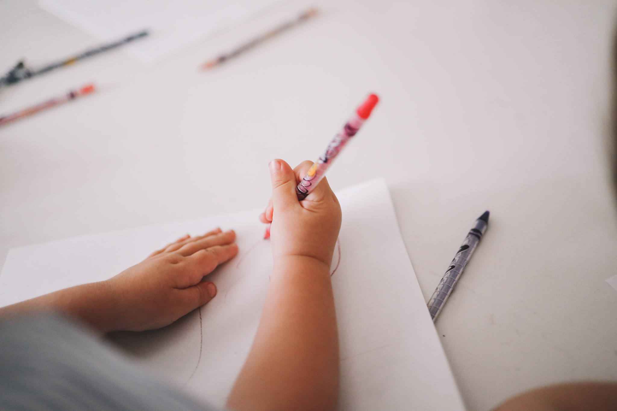 child's hand holding crayola